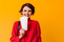 cheerful woman with short hair holding tickets neu
